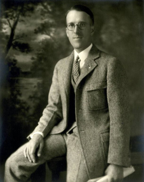 An old black and white photo of a white man with glasses in a suit.